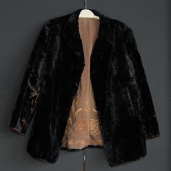 A photo of a coat that belonged to stewardess and nurse Violet Jessop. The outside of the coat is black and the lining is a shade of peach.