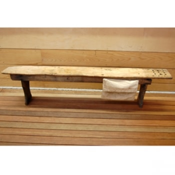 A photo of a wooden bench with a canvas bag hanging from the right-hand side.