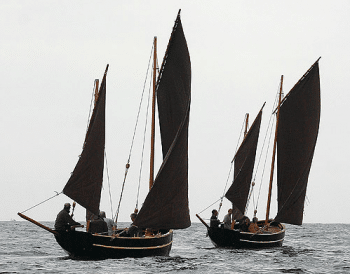 A photo of two Cornish luggers sailing one behind the other.