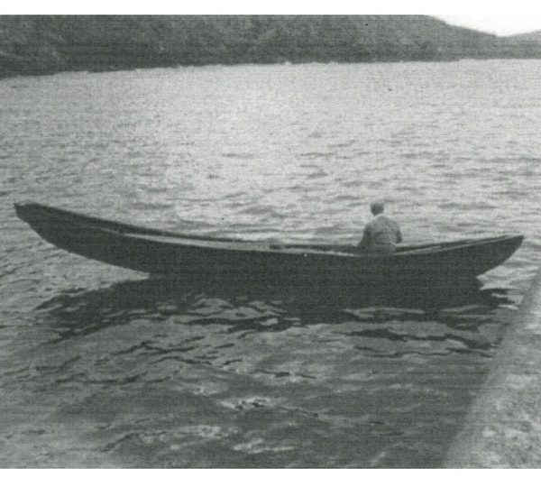 A black and white photo of a man sailing in a curragh.