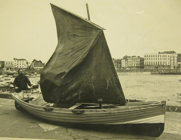 A sepia photo of a man standing behind the 'Haughty Belle'.
