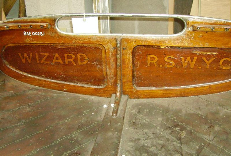 A photo of the stern of the 'Wizard', showing its name and 'R.S.W.Y.C.' carved into the woodwork.