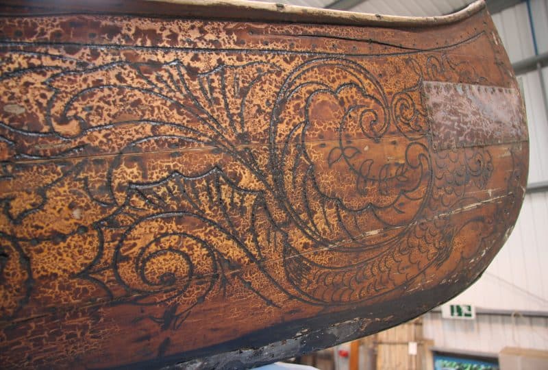 A photo of carvings in the wood of a strip plank canoe.