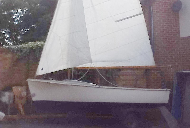 A photo of the Tod dinghy positioned on a stand in front of a brick wall.