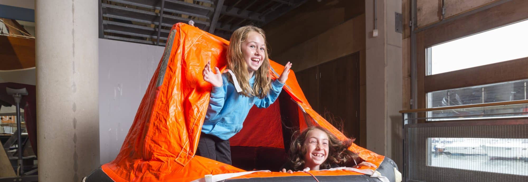 A photo of a young girl and boy playing in the life raft that was on display in the Museum's Nav Station.