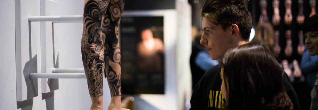Two students examine a pair of tattooed silicone hands on display at the Museum as part of the 'Tattoo: British Tattoo Art Revealed' exhibition.