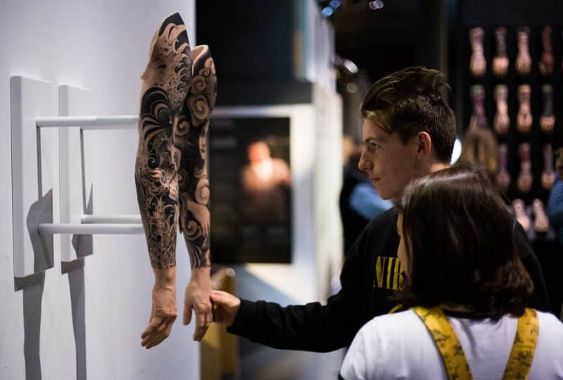 Two students examine a pair of tattooed silicone hands on display at the Museum as part of the 'Tattoo: British Tattoo Art Revealed' exhibition.