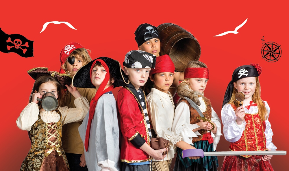 A photo of eight children dressed in pirate costumes, standing against a red background.