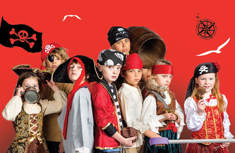 A photo of eight children dressed in pirate costumes, pictured against a red background.