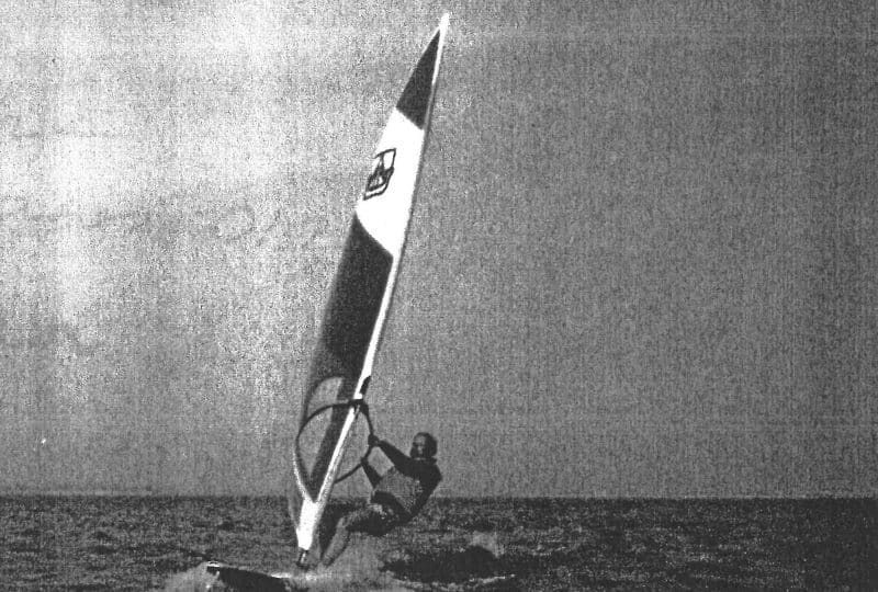 Black and white photo of a man surfing on the Dufour sailboard.
