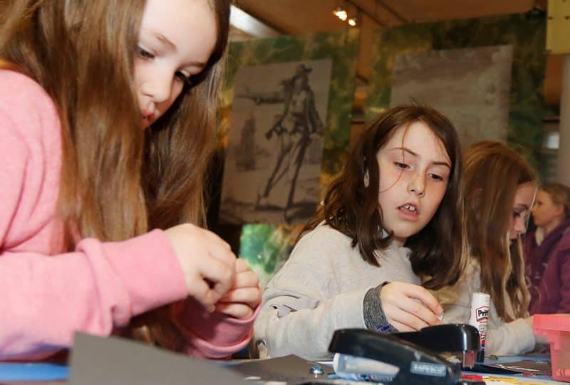 Two young girls take part in crafting activities.
