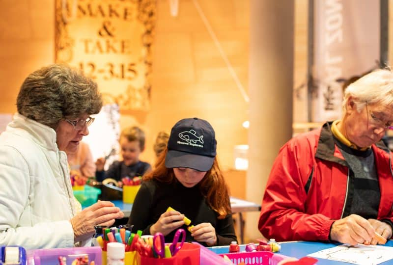 A young girl and her grandparents take part in crafting activities.
