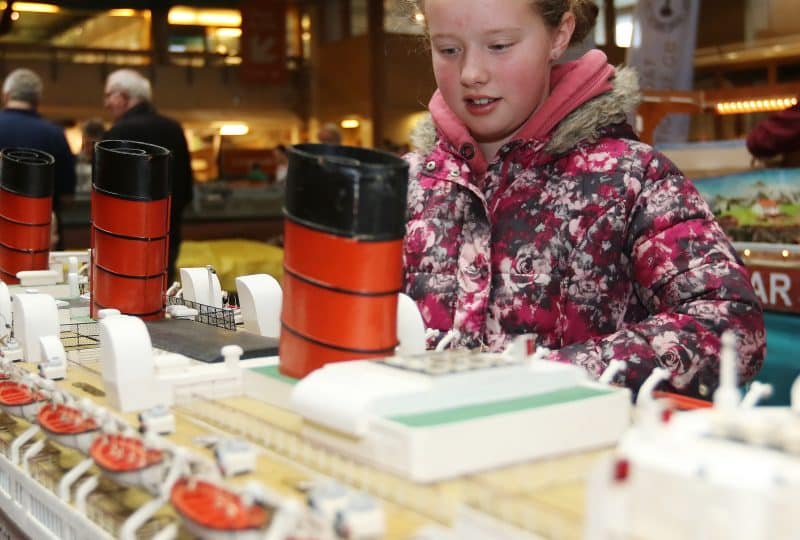 A young girl examines a model boat.