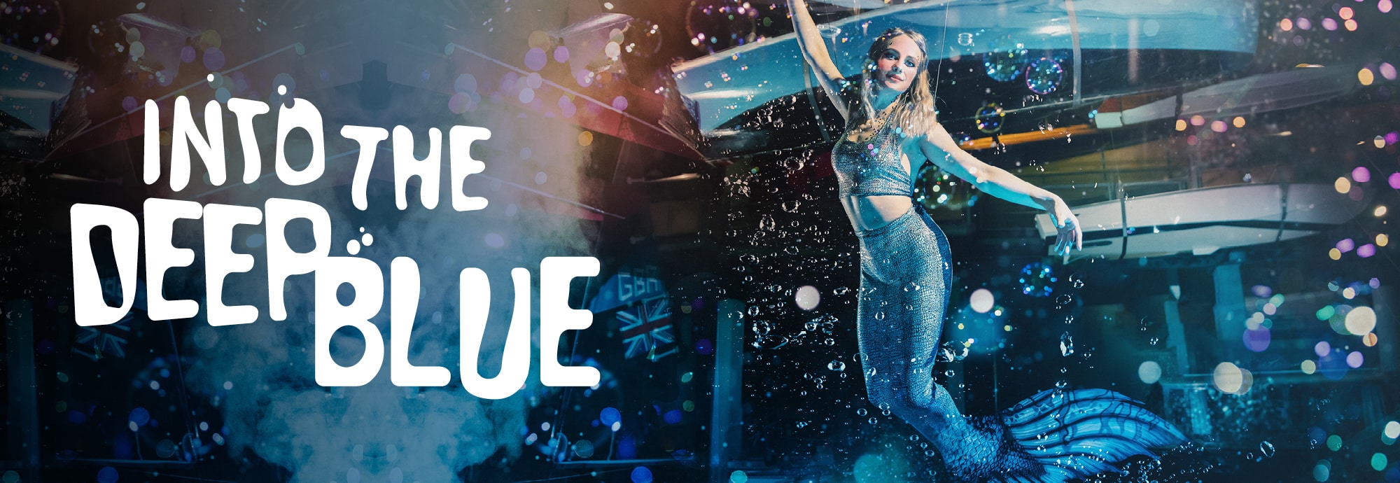 On the left of the image, white text reads 'Into the Deep Blue'. On the right, a lady in a mermaid costume is suspended in mid-air.
