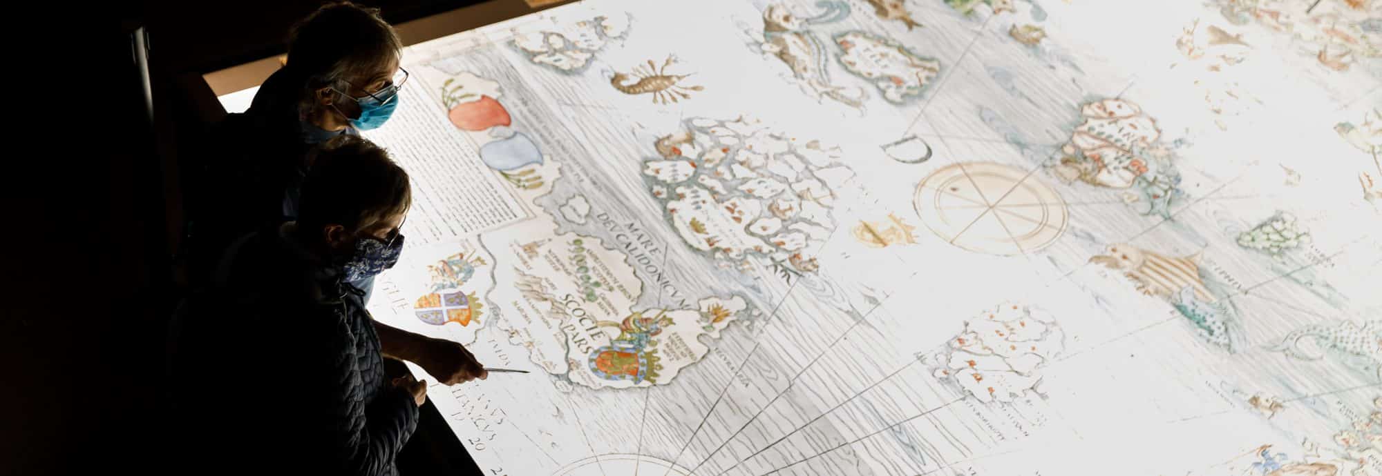 Photo of two visitors examining a large map in the Museum's 'Monsters of the Deep' exhibition.