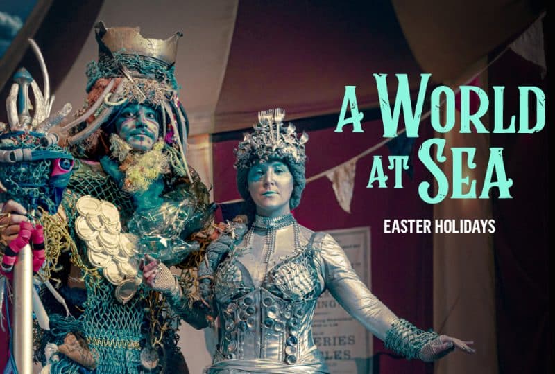 On the right of the image is text reading 'A World at Sea - Easter Holidays'. On the left is a man and a woman in costumes made out of rubbish that often finds its way into the sea.