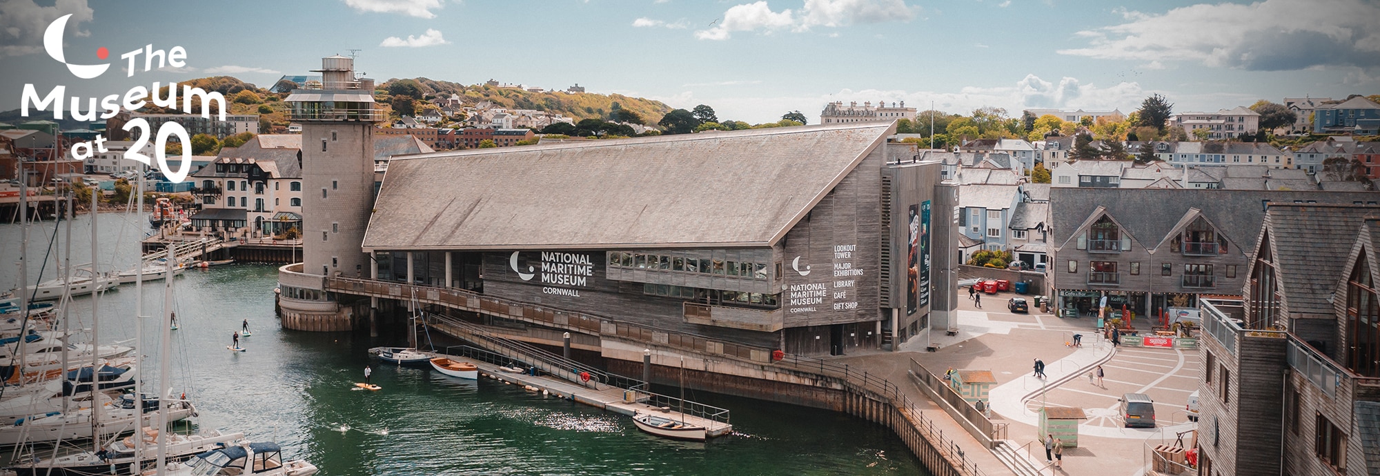 An aerial shot of National Maritime Museum Cornwall with Discovery Quay to the right and the harbour to the left. 'The Museum at 20' is written in the top left.