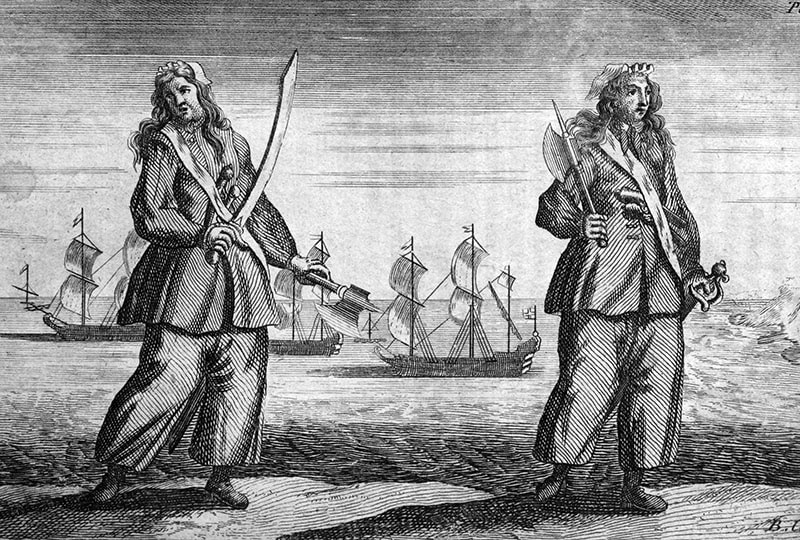 Black and white illustration of two female pirates, both brandishing weapons. In the background, three large ships sail away from land.