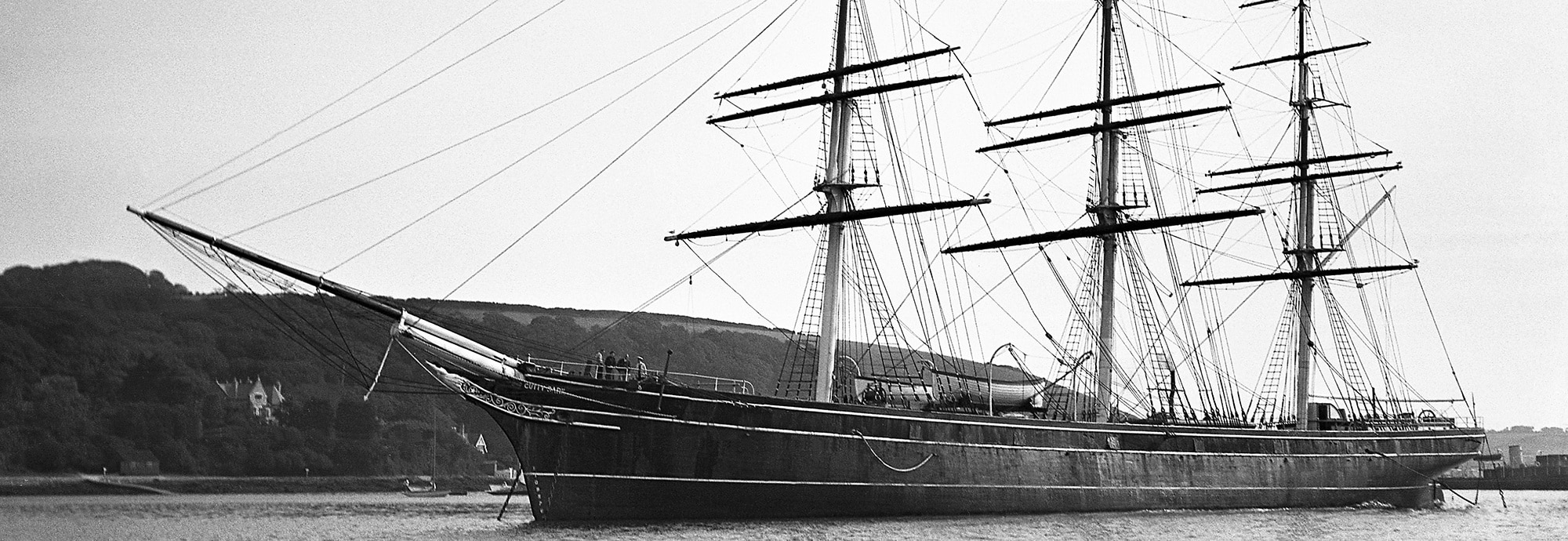 Black and white image of the Cutty Sark moored in Falmouth Harbour, taken side-on.