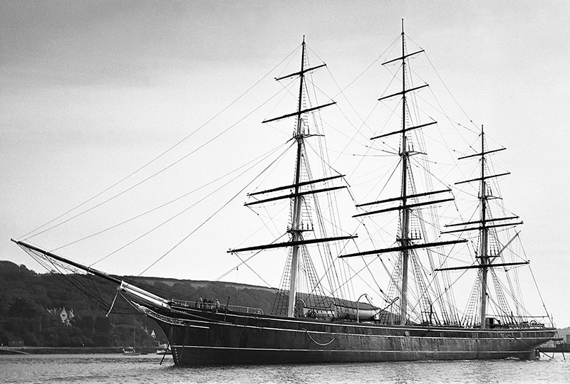Black and white image of the Cutty Sark moored in Falmouth Harbour, taken side-on.