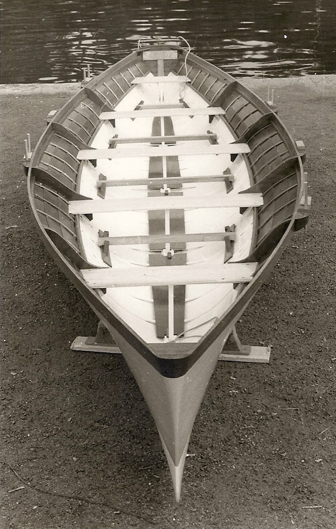 A black and white photo of a wooden rowing boat named An Gof.