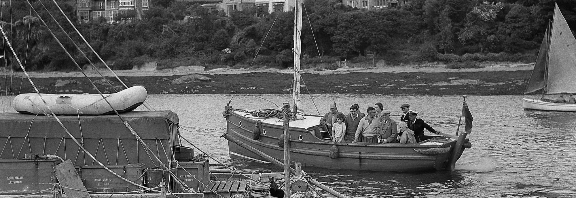 Black and white photo of the L'Egare and a boat carrying people who have come to have a look at it.