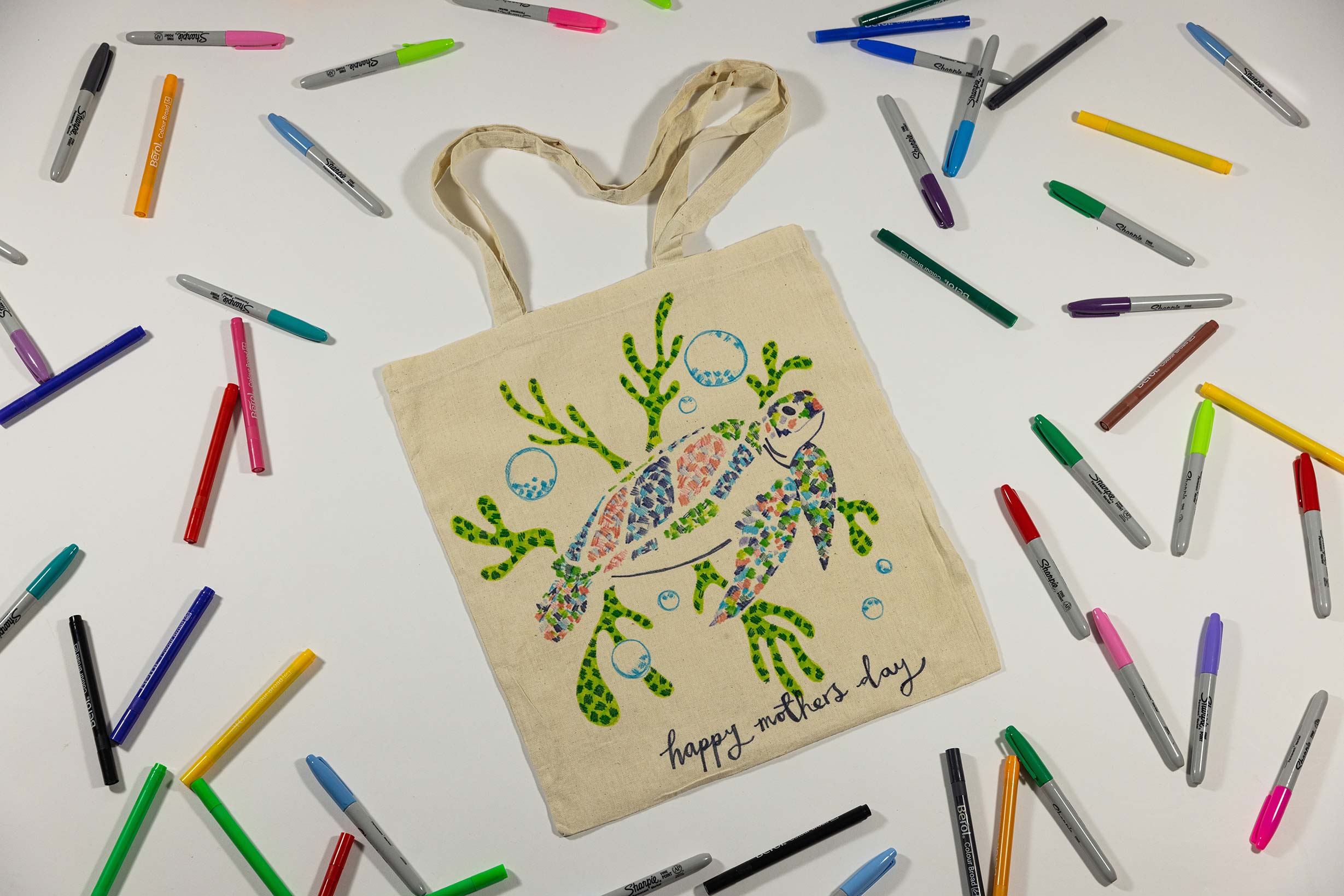 A tote bag with a turtle, some seaweed and the phrase 'happy mother's day' drawn on it.