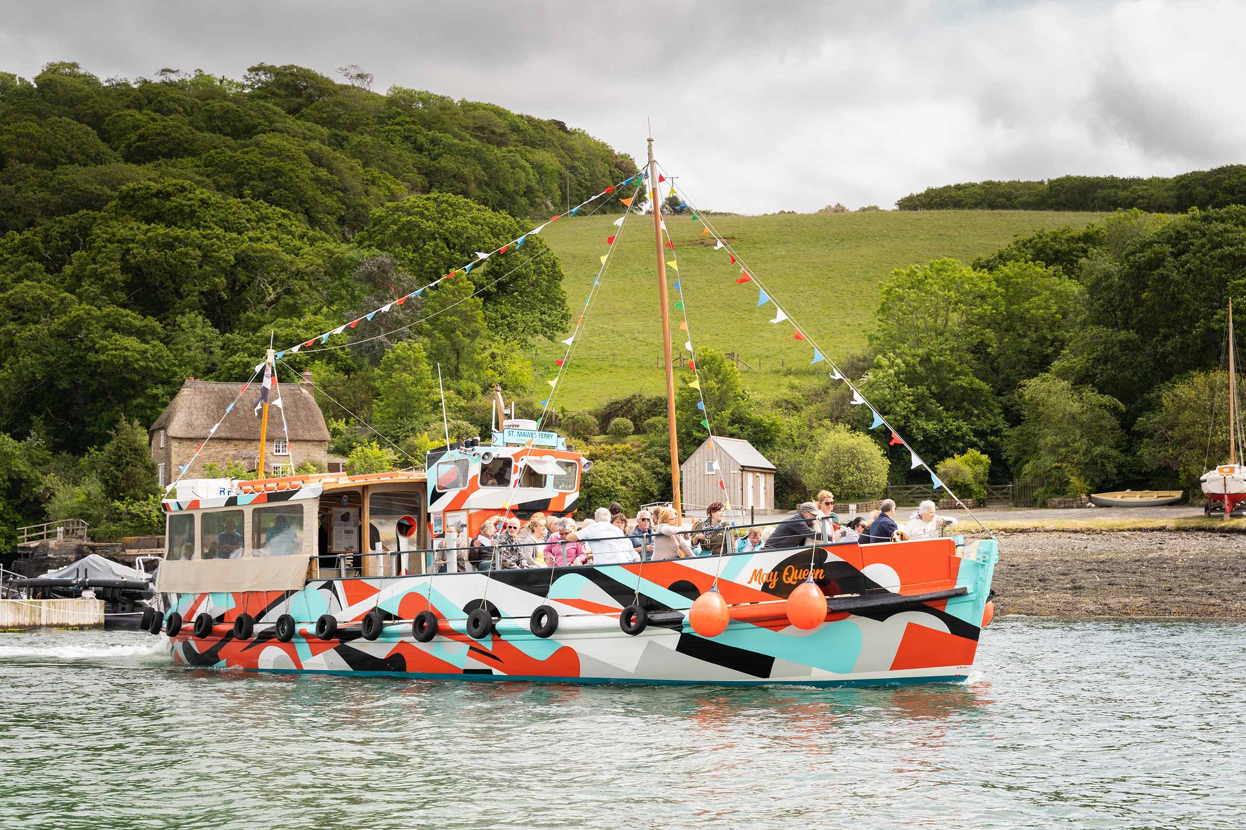 The ferry 'May Queen' carries passengers along the Fal River, decorated in its orange, white and light blue dazzle livery.