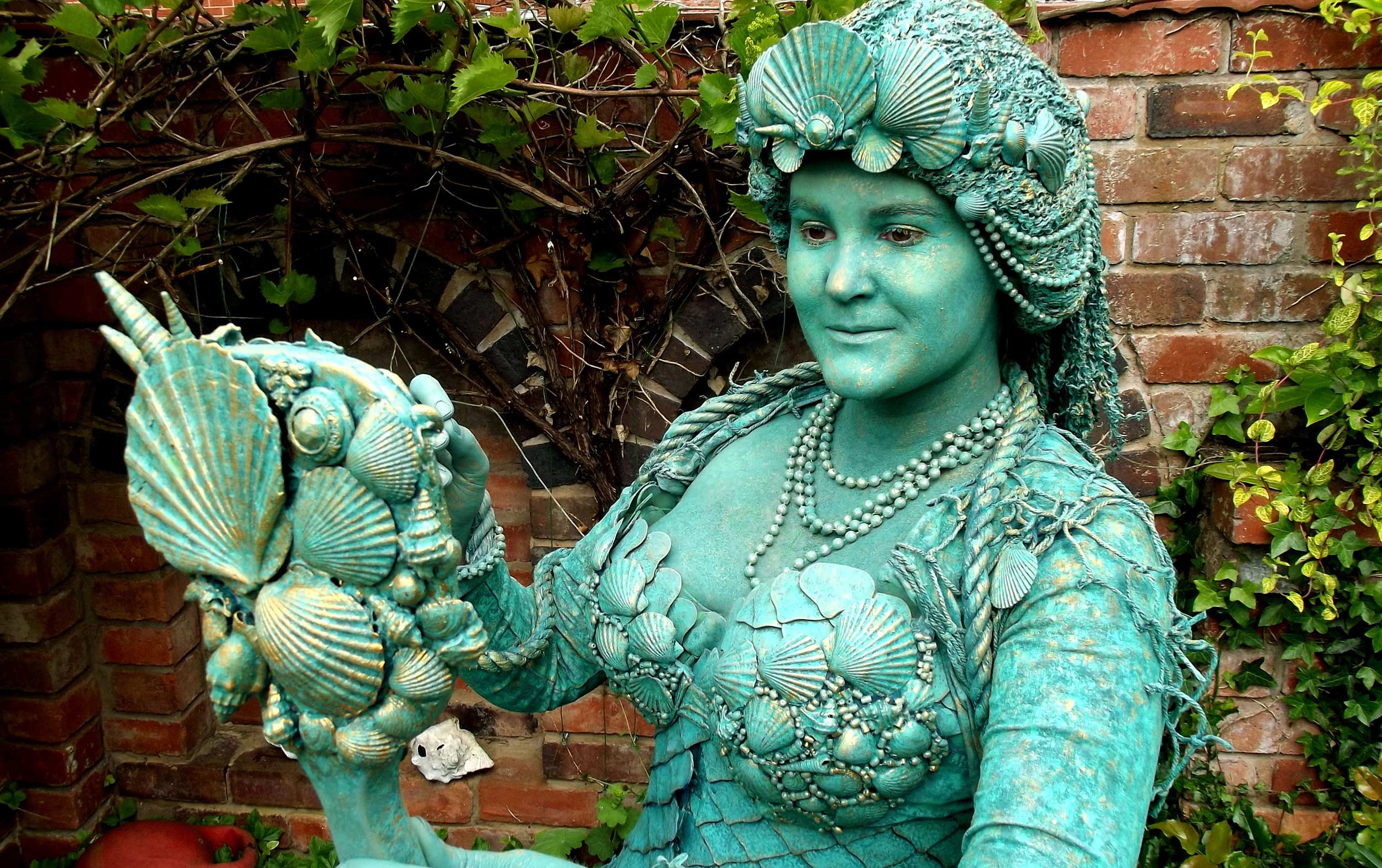 A woman dressed in a mermaid costume maid from recycled plastics and ocean waste.