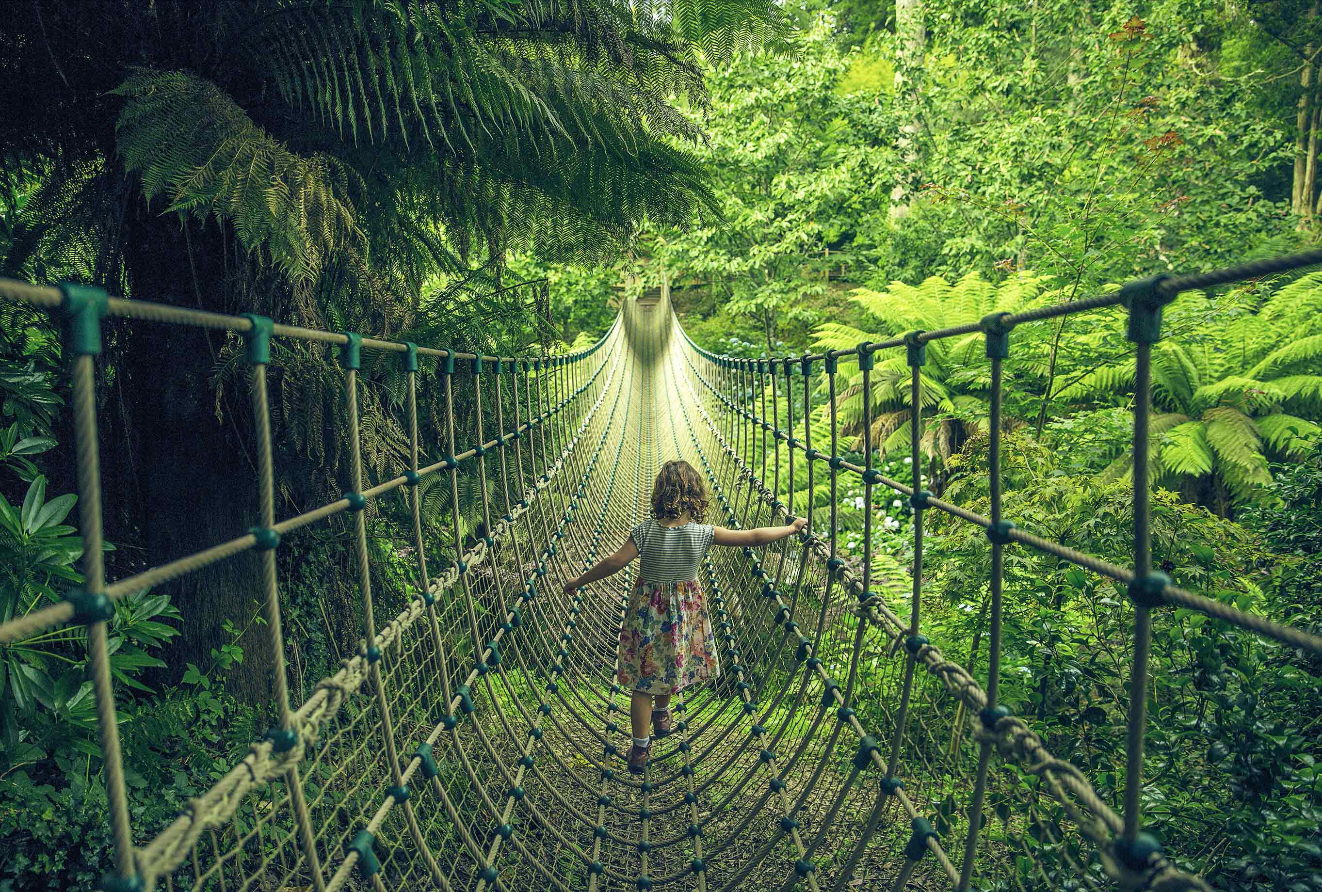 Photo of a young girl crossing a rope bridge at the Lost Gardens of Heligan.