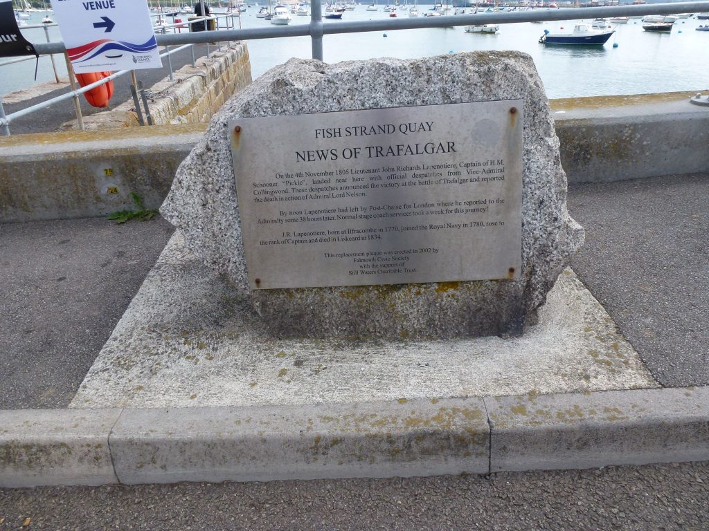 A photo of the News of Trafalgar Memorial in Falmouth; a granite stone with a plaque that reads: FISH STRAND QUAY NEWS OF TRAFALGAR On the 4th November 1805 Lieutenant John Richards Lapenotiere, Captain of HM Schooner “Pickle” landed near here with official despatches from Vice-Admiral Collingwood. These despatches announced the victory at the battle of Trafalgar and reported the death in action of Admiral Lord Nelson. By noon Lapenotiere had left by Post-Chaise for London where he reported to the Admiralty some 38 hours later. Normal stagecoach services took a week for this service! JR Lapenotiere, born at Ilfracombe in 1770, joined the Royal Navy 1780, rose to the rank of Captain and died in Liskeard in 1834. This replacement plaque was erected in 2002 by Falmouth Civic Society with the support of Still Waters Charitable Trust