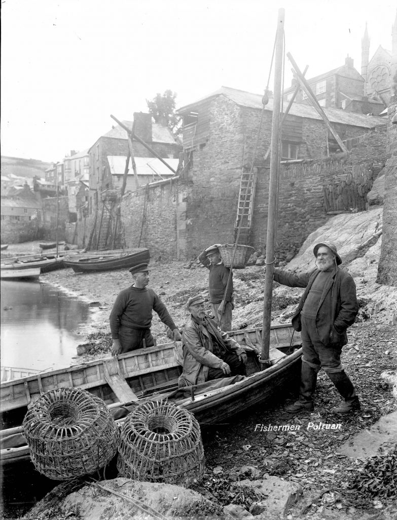A black and white photo of Cornish fishermen on a small beach.