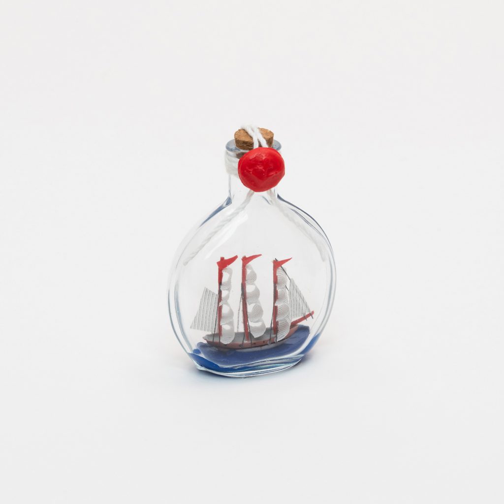 A ship with white sails in a round bottle with a cork and a red seal.