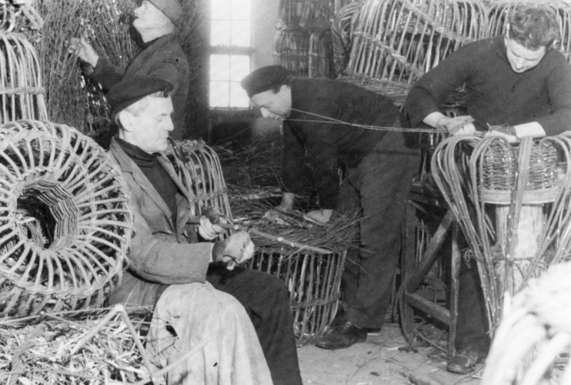 A black and white photo of fishermen building lobster pots.