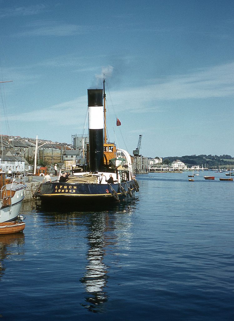 The Falmouth Towage Company tug Lynch alongside North Quay with flag flying at half-mast is on a funeral service mission as there is a Minister on deck starboard side. Taken during August 1957.