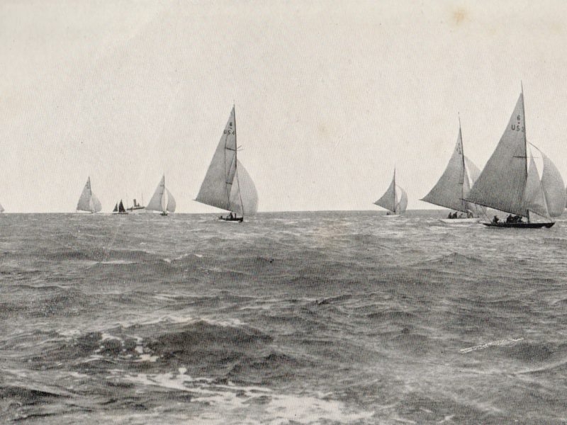 A black and white photo of sailing boats racing at sea.