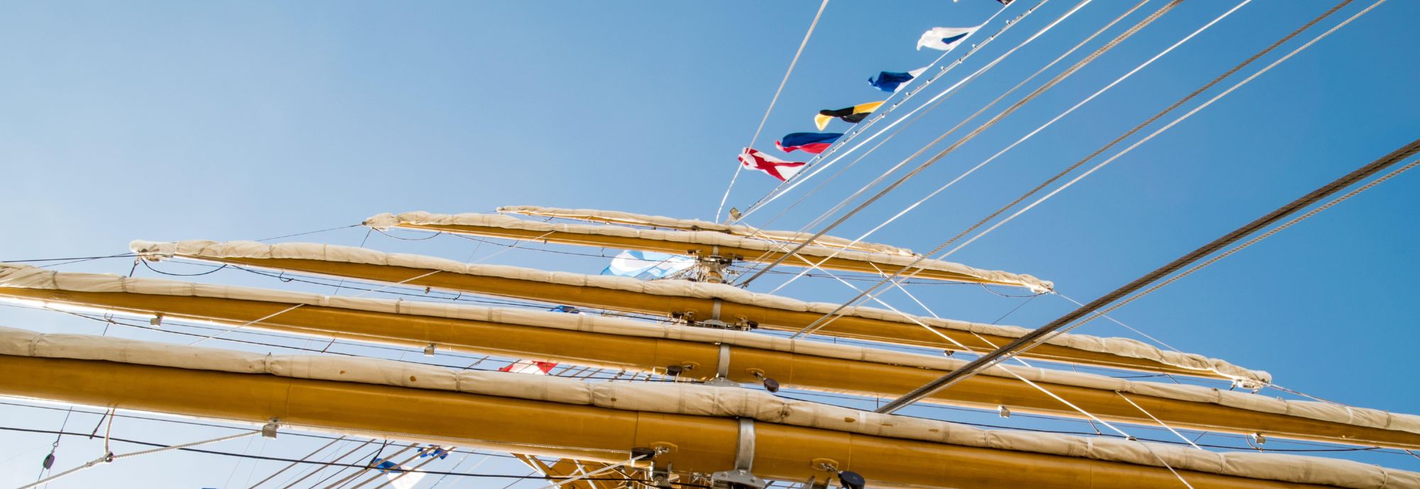 A tall ship's masts with nautical flags flying.