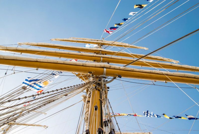 A tall ship's masts with nautical flags flying.