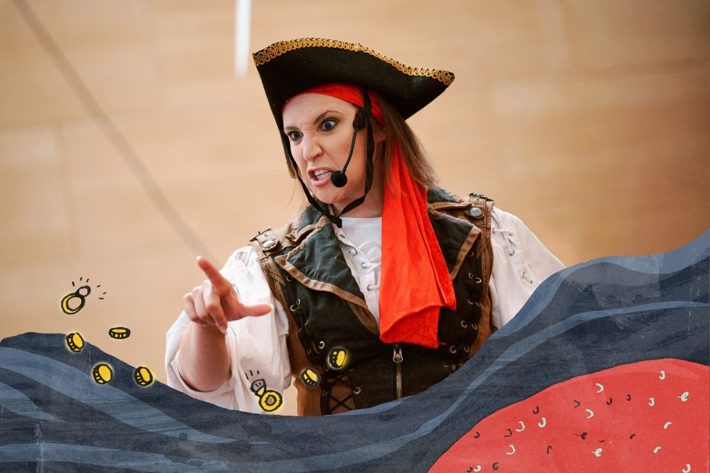 A member of the cast in National Maritime Museum Cornwall's summer show wearing a pirate outfit on stage. There is a graphic overlay of blue waves, a red octopus tentacle, and golden coins.