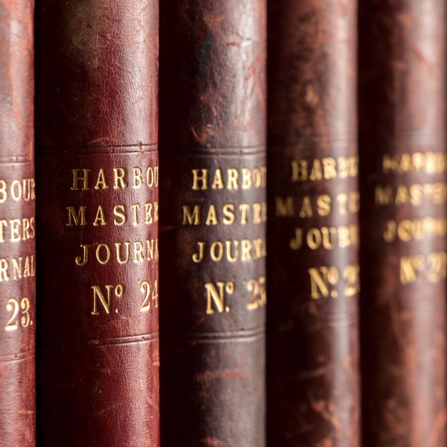 A close-up photo of the spines of brown books labelled Harbour Masters Journal.