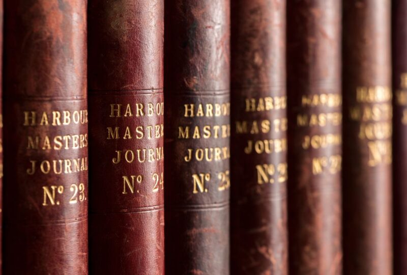 A close-up photo of the spines of brown books labelled Harbour Masters Journal.