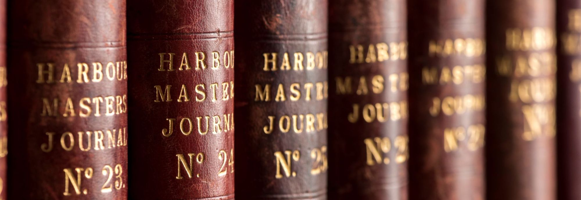 A close-up photo of the spines of brown books labelled Harbour Masters Journal.