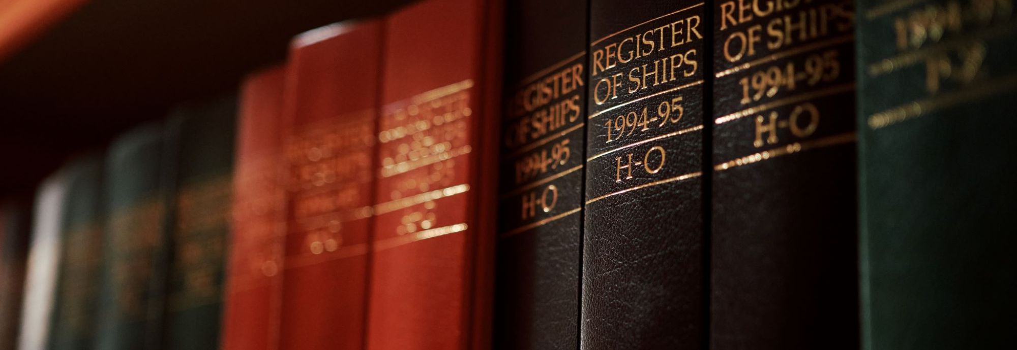 Close-up of red, black, and green books on a bookshelf.