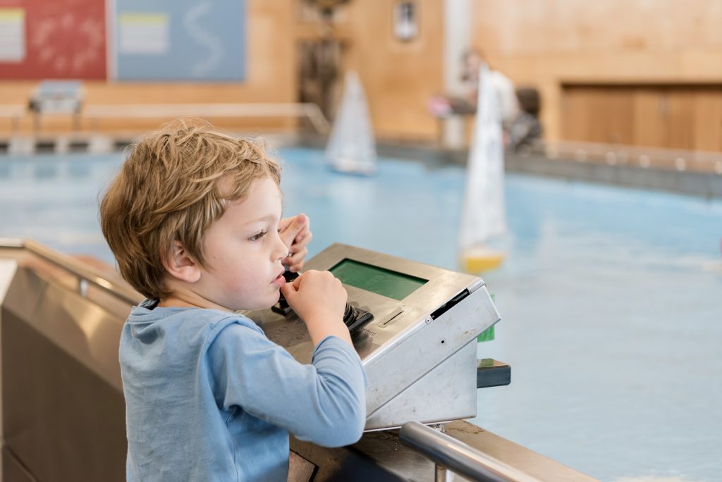 A young boy operating the controls of a remote control boat at National Maritime Museum Cornwall's Boat Pool.