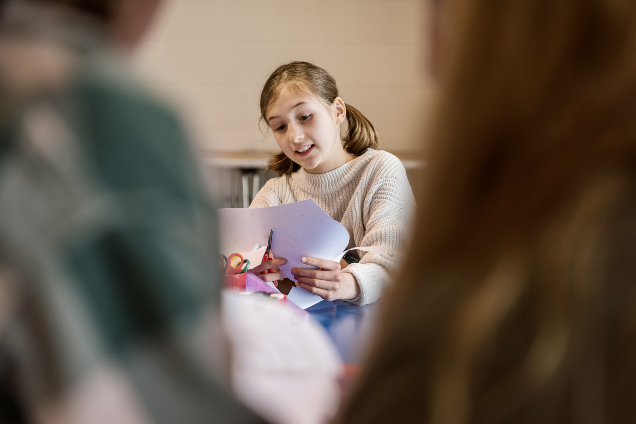 A girl using scissors to cut up paper in a craft workshop at National Maritime Museum Cornwall.