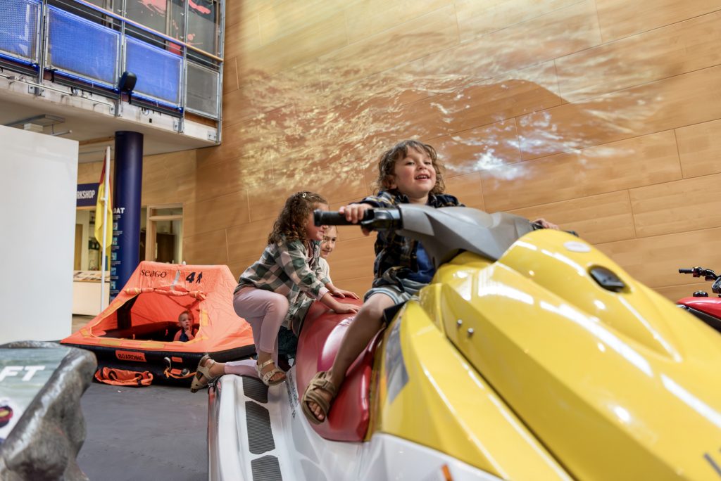 The RNLI Rescue Zone at National Maritime Museum Cornwall. Children are playing on a lifeguard jet ski and another child is playing in a life raft.