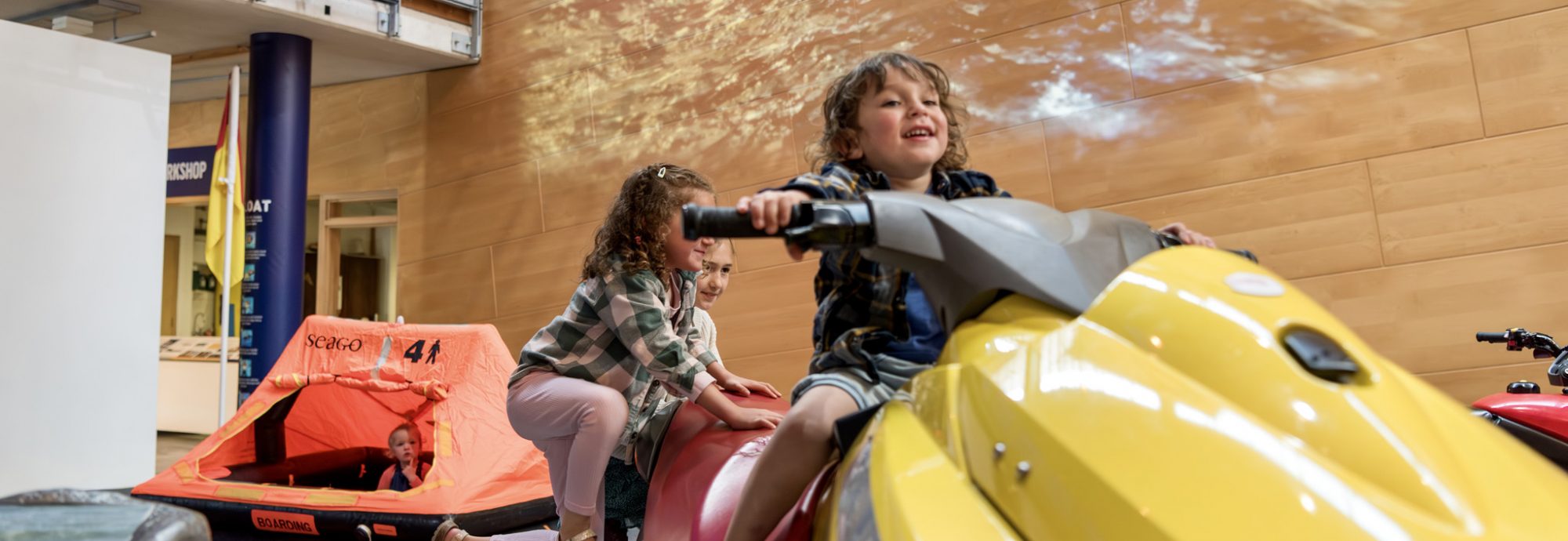 The RNLI Rescue Zone at National Maritime Museum Cornwall. Children are playing on a lifeguard jet ski and another child is playing in a life raft.