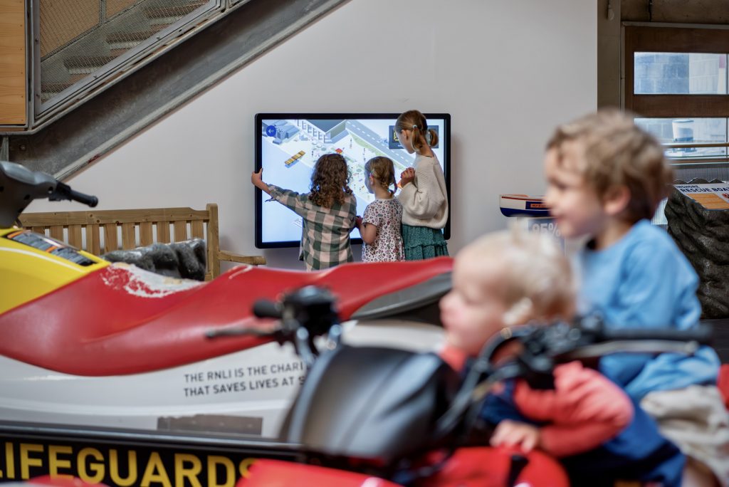 The RNLI Rescue Zone at National Maritime Museum Cornwall. Two children play on a quad bike while three other children use an interactive screen.