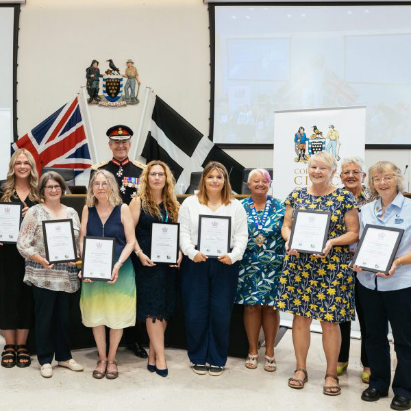 A group photo of all of nominees for the Kings Award for Voluntary Service holding their certificate.