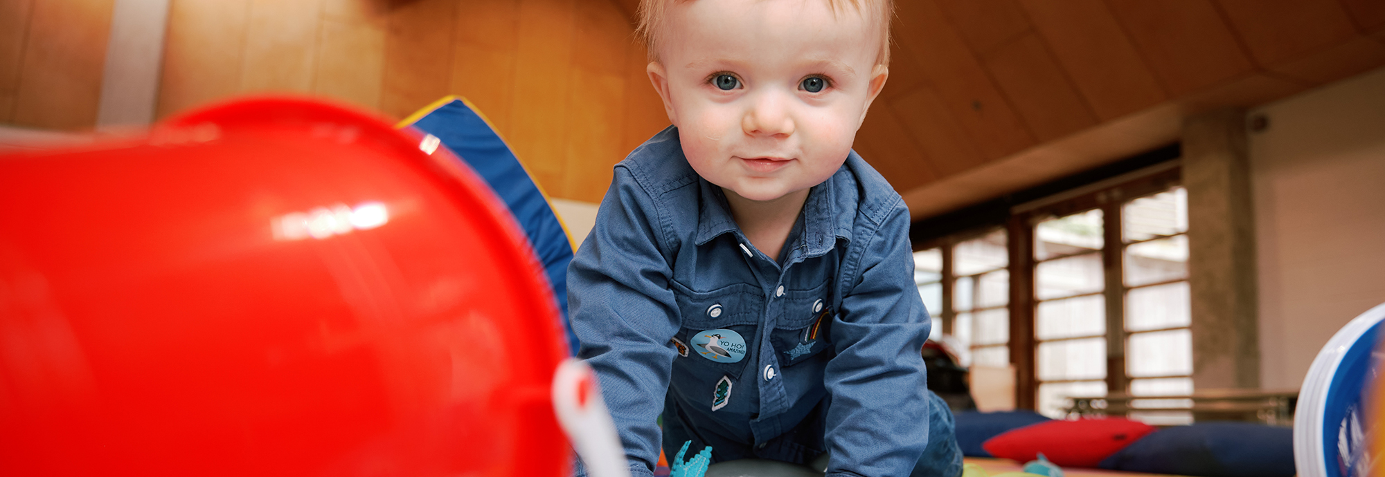 A small child looks at the camera, surrounded by toys.